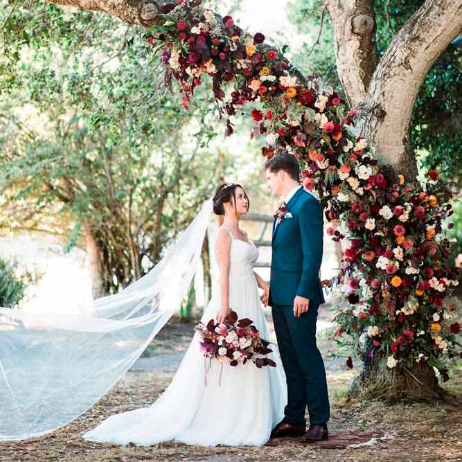 A Ceremony Arch Out Of The Tree Branch With Floral Decorating #outdoorweddingarch #flowersweddingarch