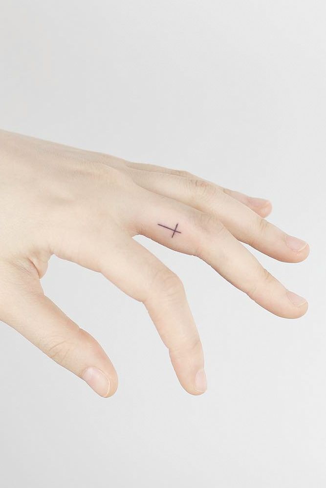 small cross tattoo on finger