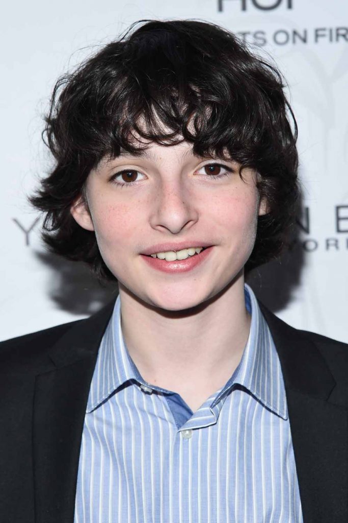 Finn Wolfhard com longos cachos escuros e desgrenhados