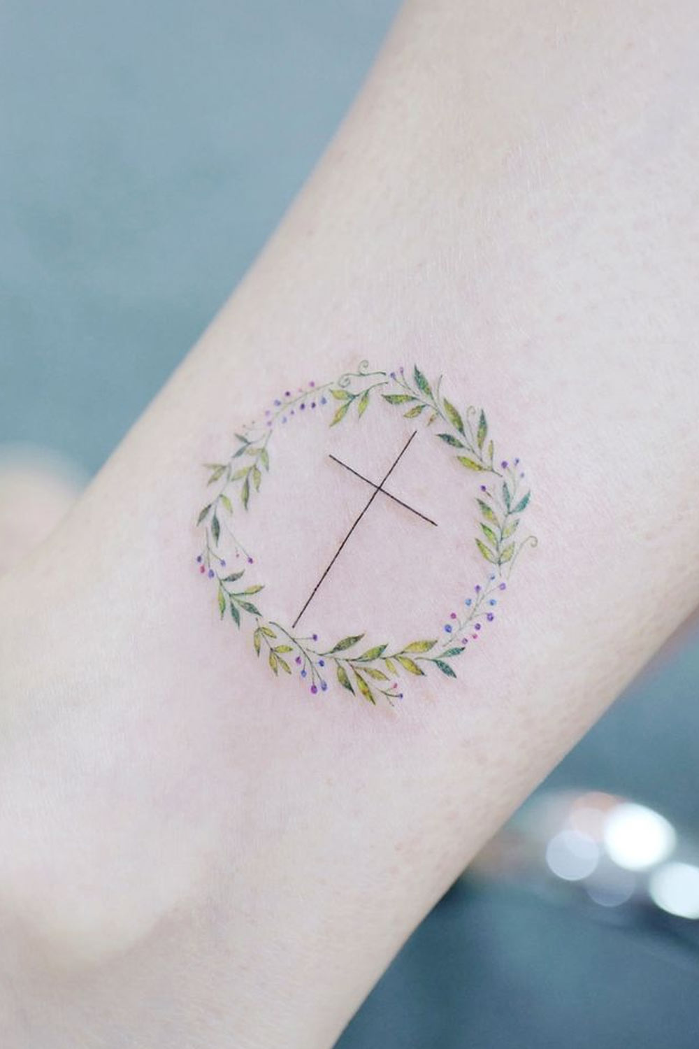 Tatuagem cruzada no tornozelo com círculo floral