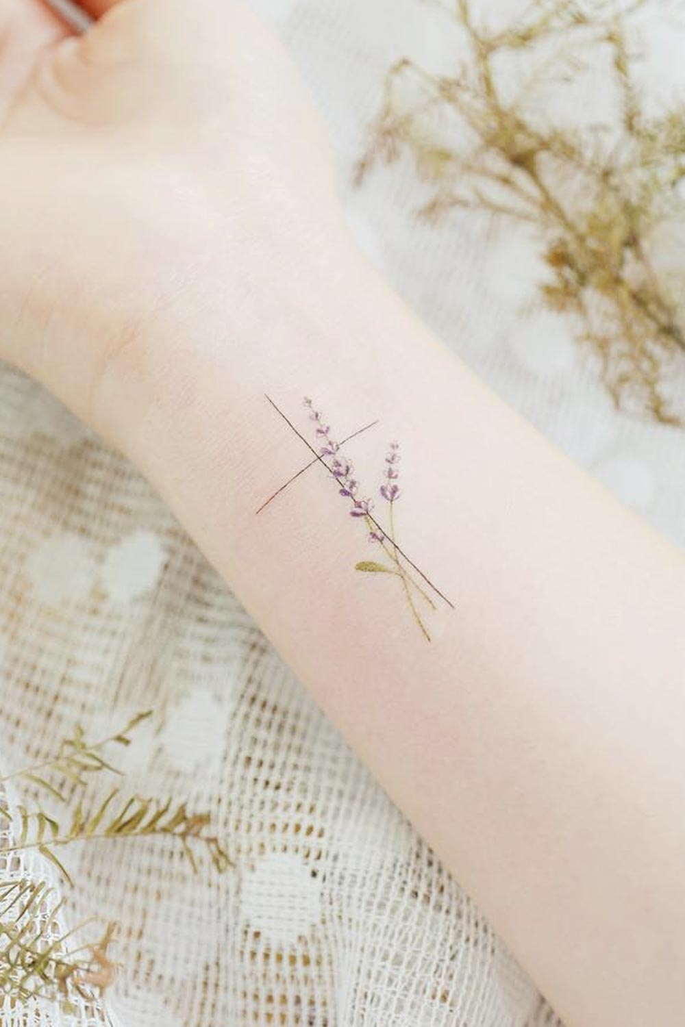 Tatuagem de pulso minimalista com cruz e flores