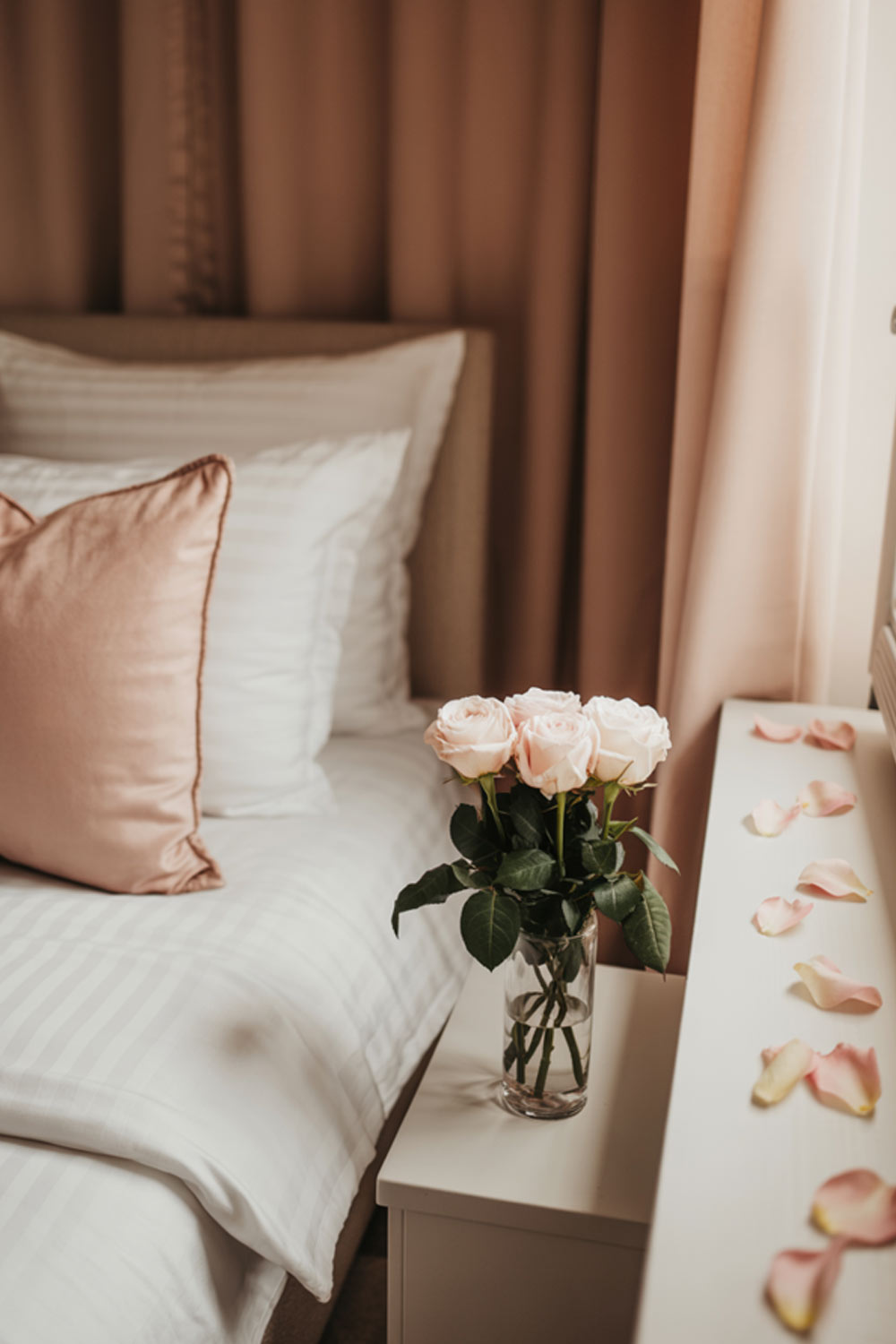 Cozy Bedroom Decor With Pink Roses In A Vase And Soft Neutral Bedding